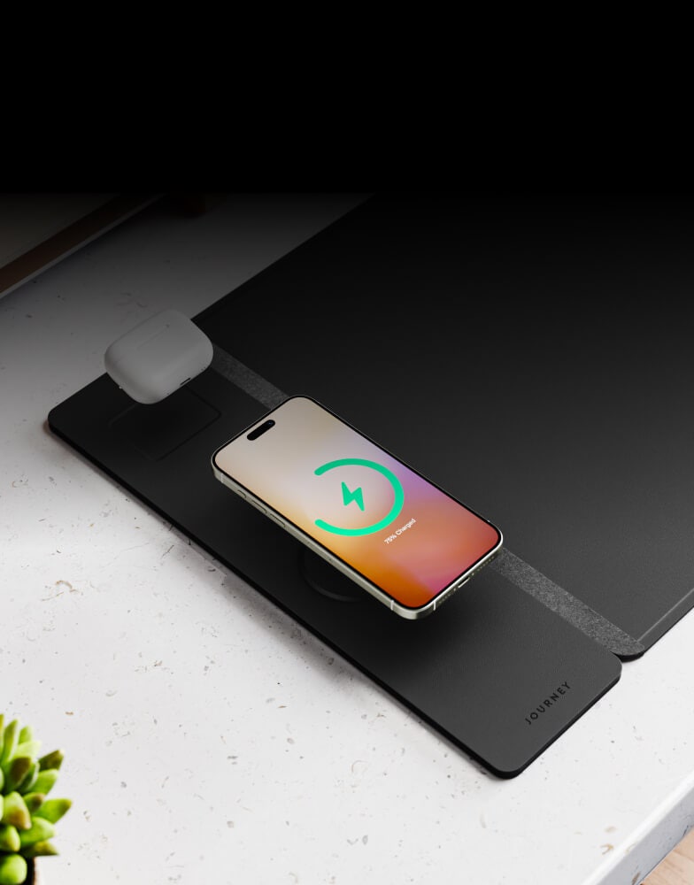 An image of the all-in-one Mac sleeve workspace charging an iPhone and AirPods wirelessly.