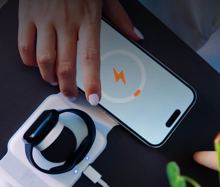 Person charging Apple Watch and iPhone on wireless charger