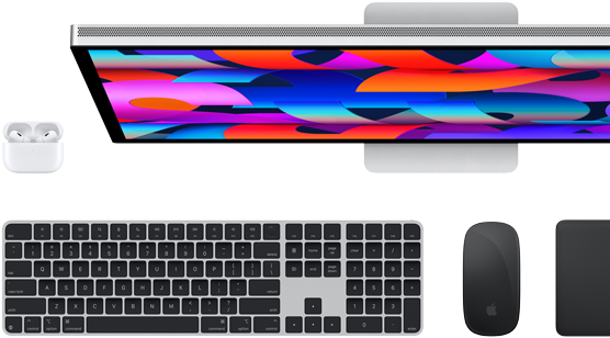 Top down view of Studio Display monitor, black Magic Keyboard, black Magic Mouse, black Magic Trackpad and white AirPods case